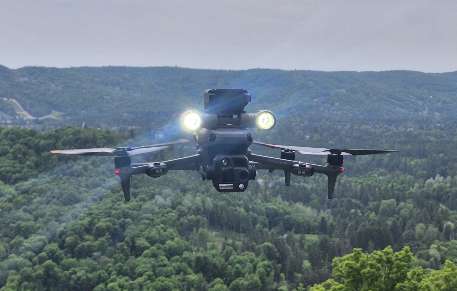 Drone Matrice avec projecteurs allumés en vol au-dessus de la forêt, captation en cours